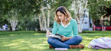 student writing in her book in the park
