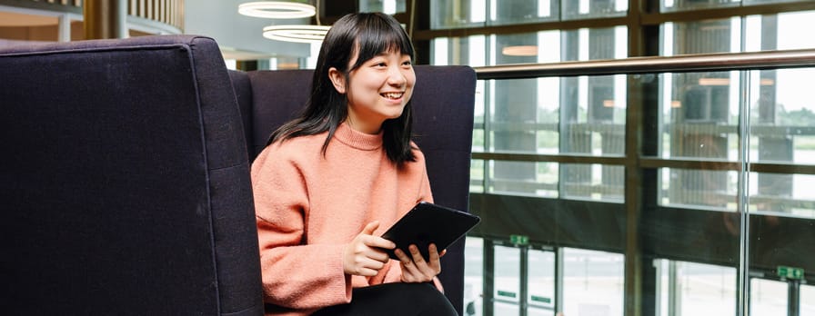 student using tablet device on couch